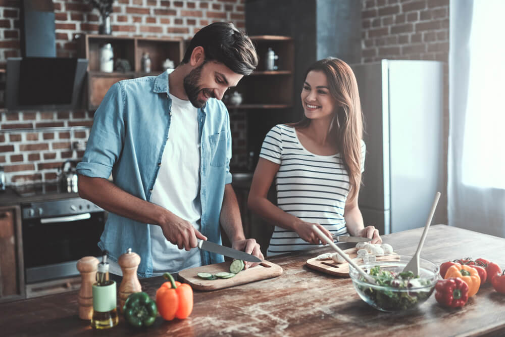 young smiling couple cooking together